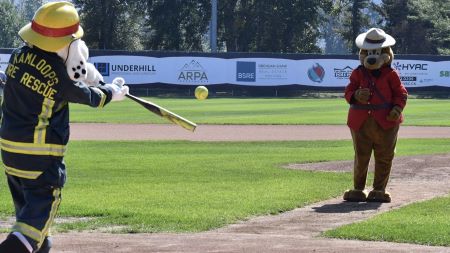 The Kamloops Fire Rescue mascot ‘Sparky’, (a dalmatian in a firefighter’s uniform), takes a swing at a softball pitched by the Kamloops RCMP mascot, Sgt Safety Bear (a bear in a Mountie Serge and hat). 