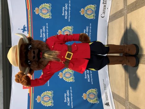 Une mascotte de bison vêtue d’une tunique rouge officielle de la GRC, portant des bottes brunes et un chapeau Stetson brun, faisant un salut d’une main.