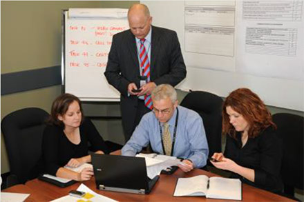 4 investigators at work on a table with laptop and papers